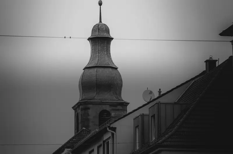 Häuserzeile in Pirmasens mit Kirchturm und Ampel unter grauem Himmel
